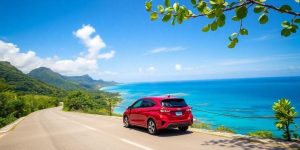 Voiture rouge sur route panoramique - location voiture Raiatea avec vue sur lagon