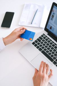 Une personne effectuant un achat en ligne avec une carte de crédit sur un ordinateur portable, présentant la technologie moderne du commerce électronique.
