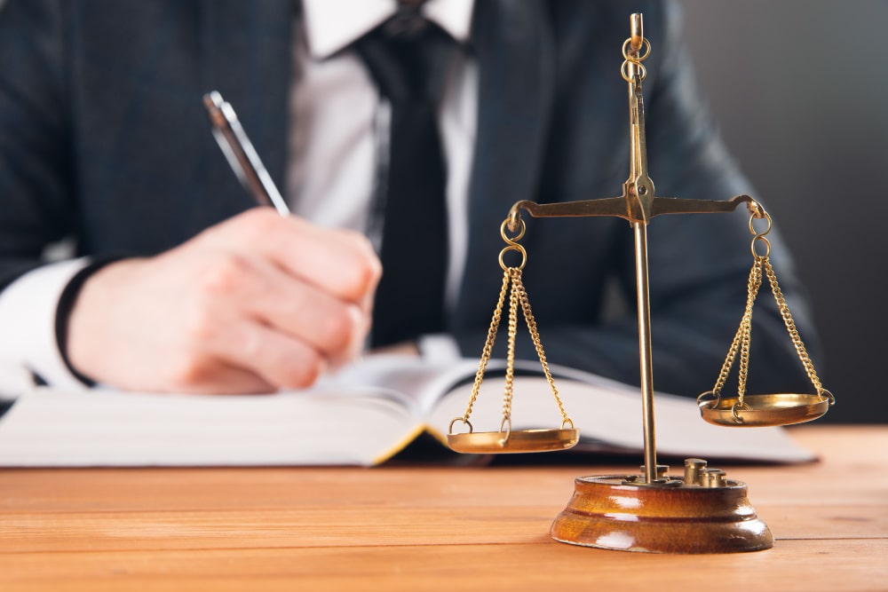 Un avocat travaille sur un dossier avec une balance de la justice. Trouver le bon avocat.