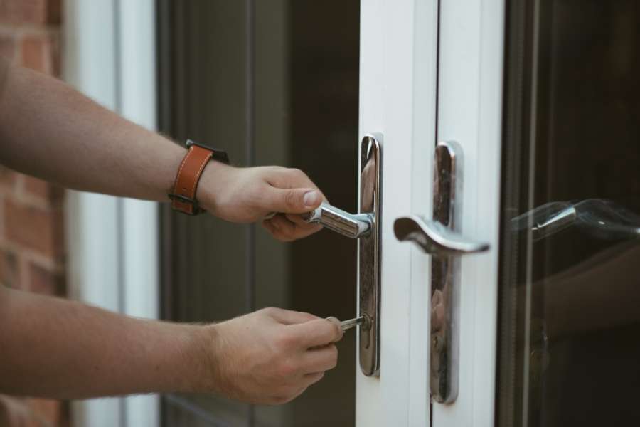 Une main insère une clé dans une serrure qui accroche sur une porte moderne. 